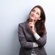 Beautiful young business woman thinking and looking up on blue background