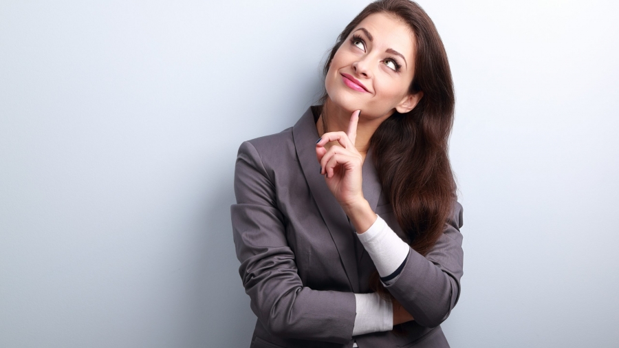 Beautiful young business woman thinking and looking up on blue background